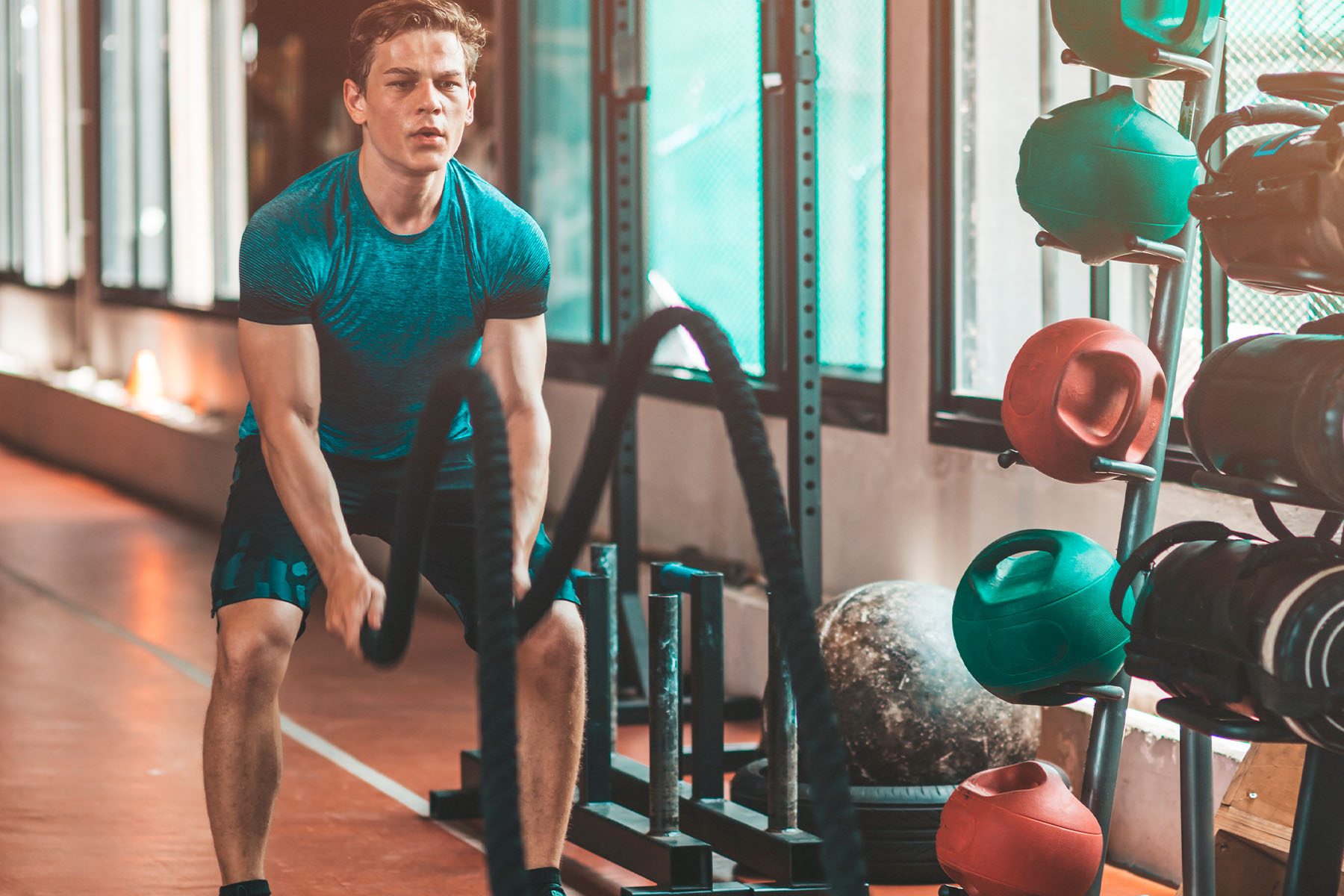 Persona entrenando con sogas de batalla en un gimnasio.